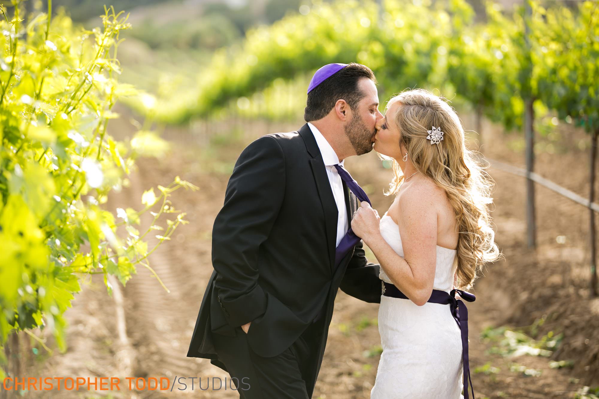 a kiss in the vineyards between bride and groom temecula winery