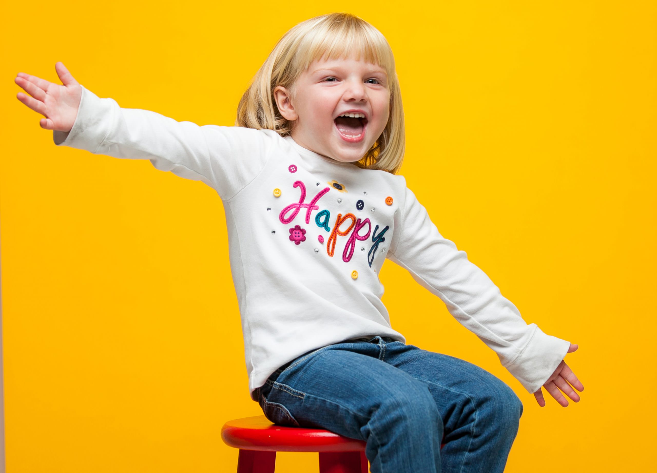 child studio portrait on red stool with yellow backdrop