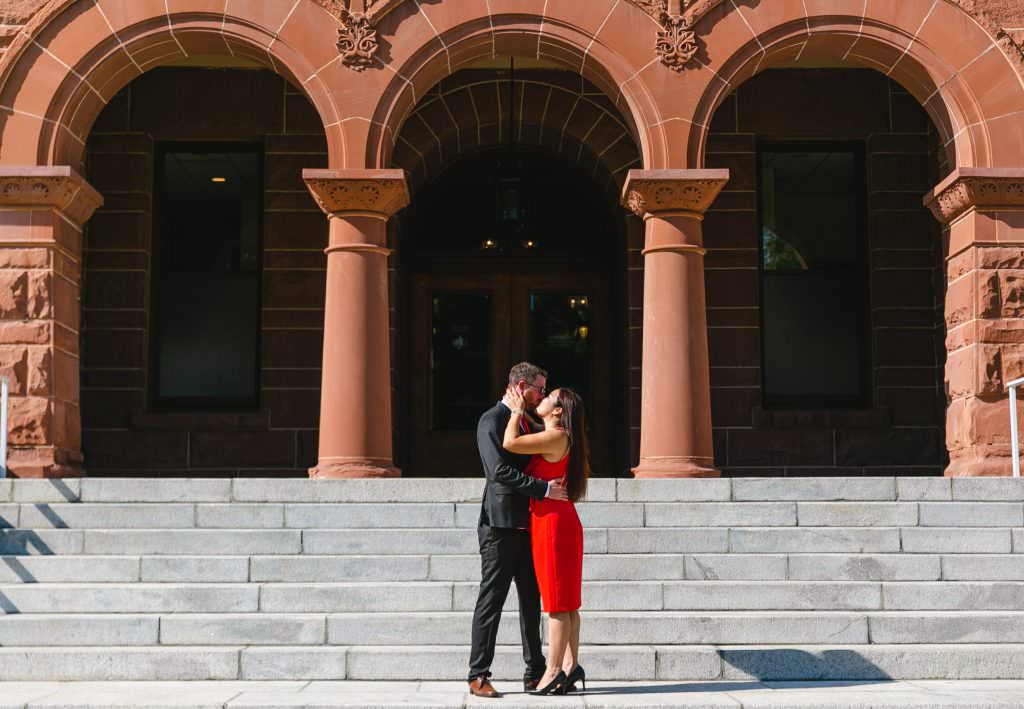 Eloping couple kisses at base of stairs at old orange county courthouse after civil wedding service.