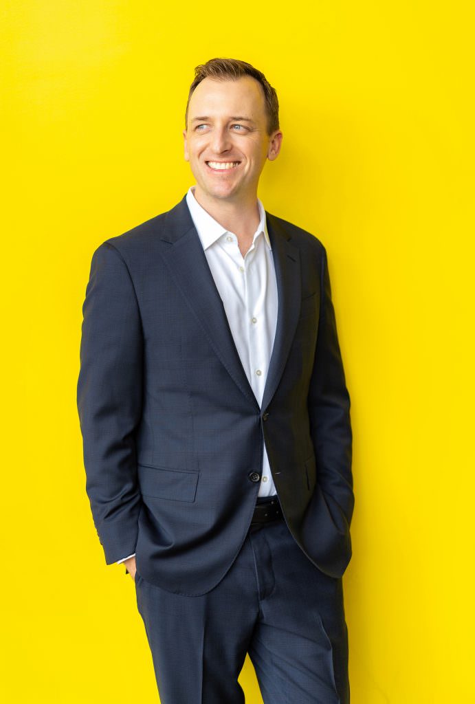 online dating headshot of man in blue suit with yellow background