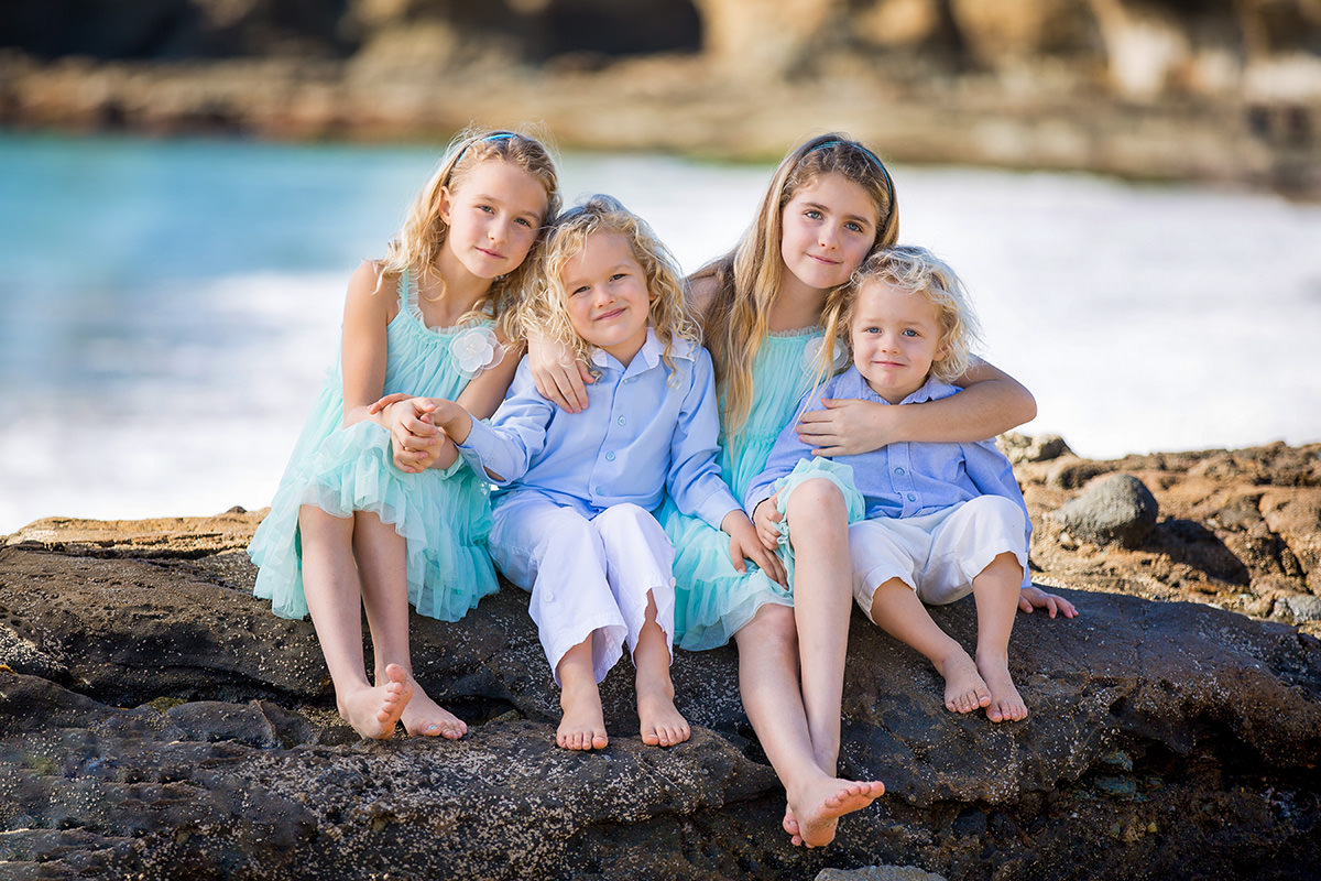 Four siblings sitting on tide pools at Laguna Beach.