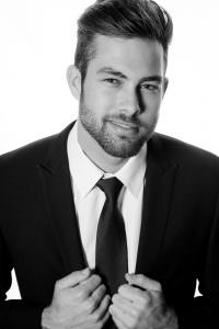Young male model headshot wearing black suit and tie.