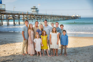 Large family standing on the sand in front of San Clemente Pier.