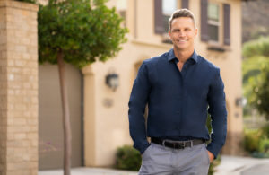 Example of branding photo man wearing button down shirt standing outside house.