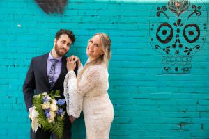 bride and groom standing in front of turquoise blue brick wall
