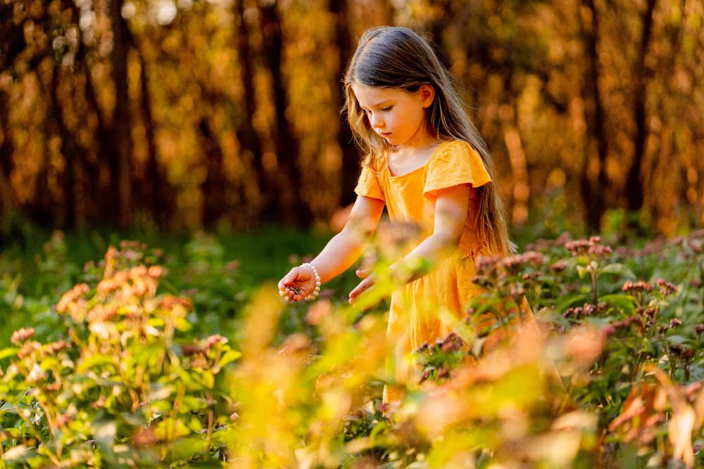 Young girl wearing yellow dress picking flowers
