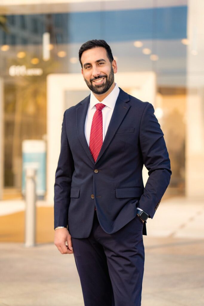 Male attorney wearing suit with red tie standing in front of building