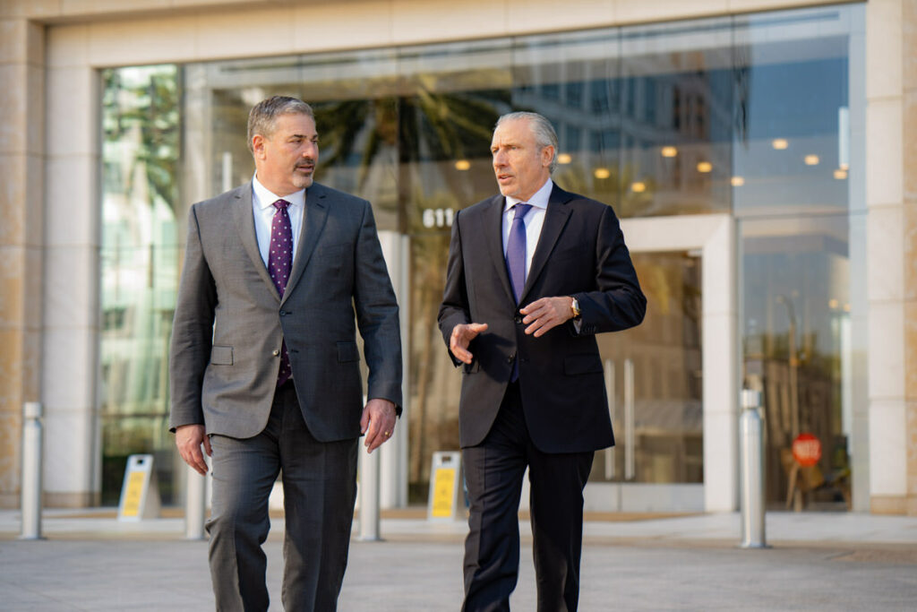 Two men walking and talking wearing business suits