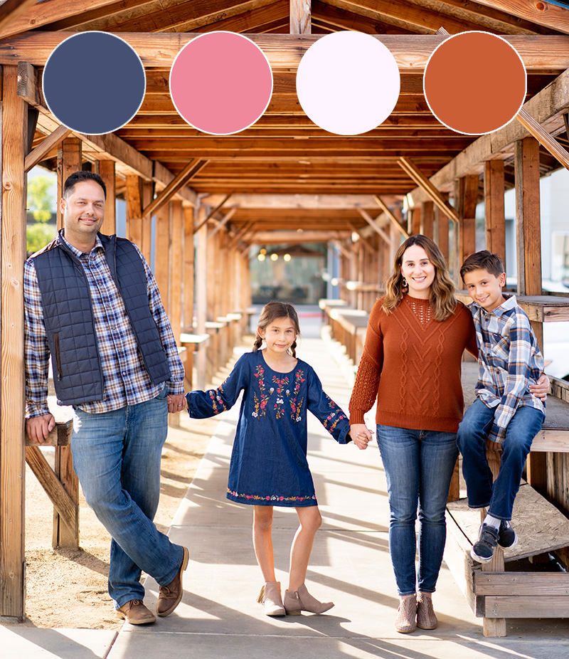 Family of four wearing fall color outfits under structure.