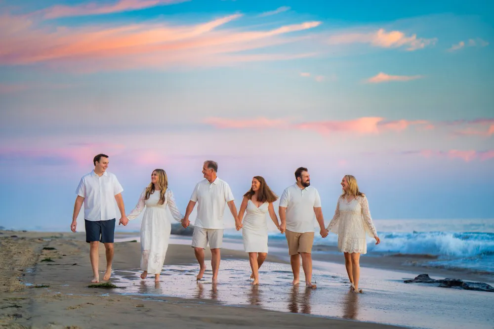 family of 6 couples holding hands walking on the beach during sunset for beach photo shoot