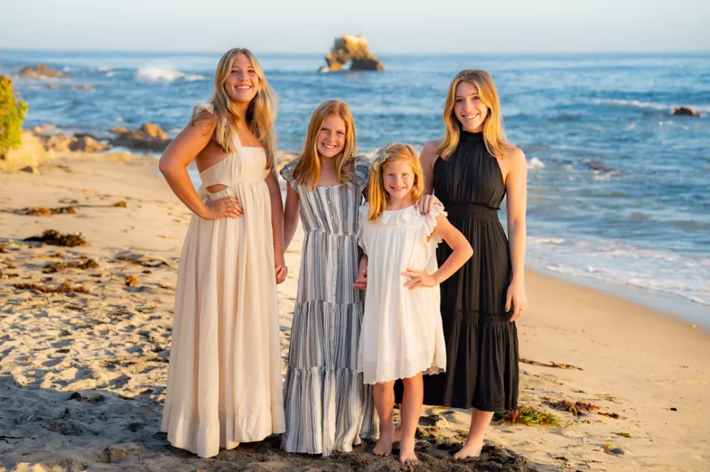 pre-teen and teen girls wearing long dresses posing on the beach for photoshoot