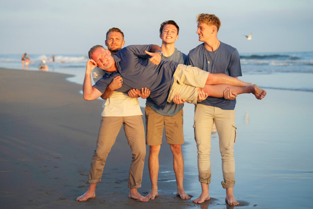 3 sons holding dad in a fun photo at Newport Beach Pier