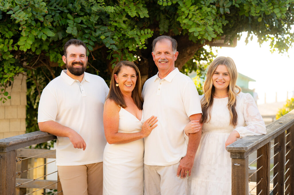 four adults wearing white and tan with tree at Crystal Cove cottages