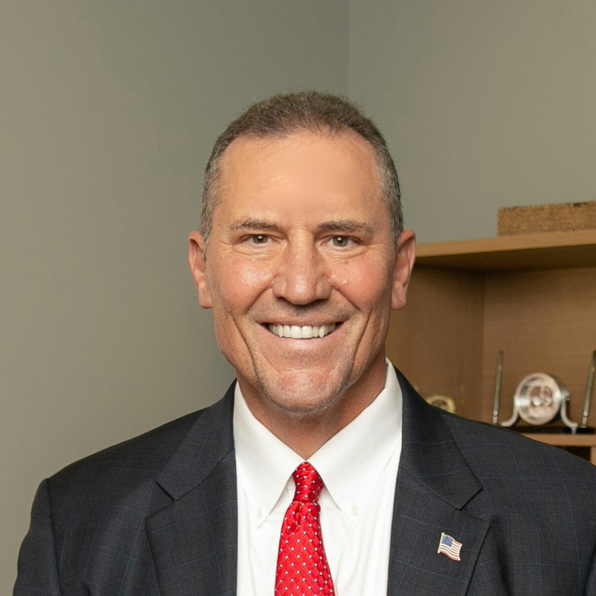 executive man with suit and red tie poses for a headshot in his office